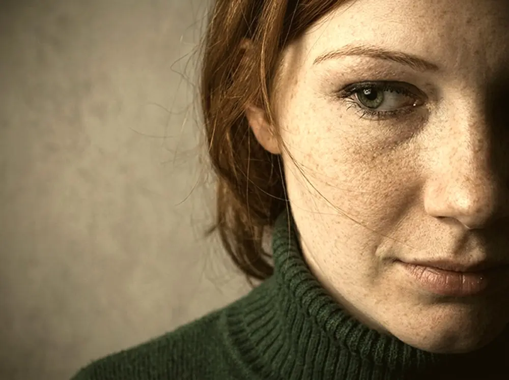 Close-up van een vrouw in een groene trui die gelaten voor zich uit kijkt